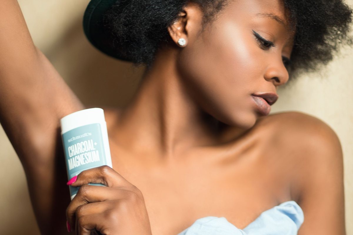 A woman applying deodorant as part of her personal care routine.