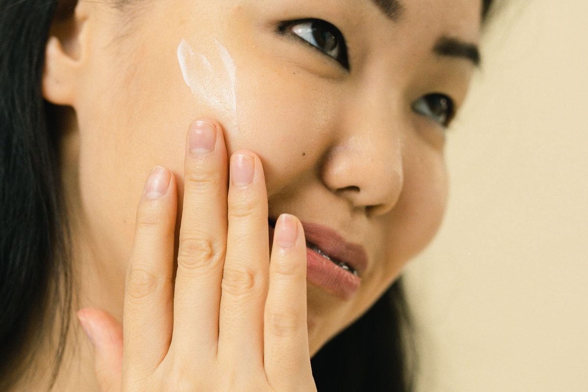 A woman gently applying face cream to her skin as part of her skincare routine.