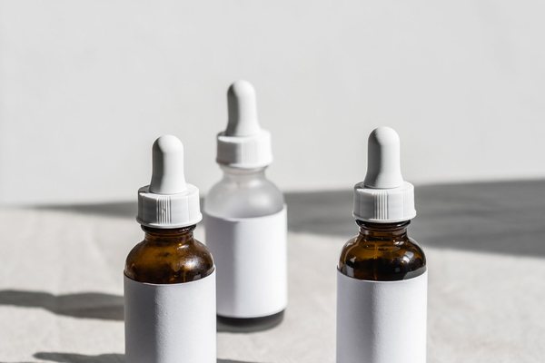 Three glass serum bottles with droppers lined up on a fabric surface in natural light.