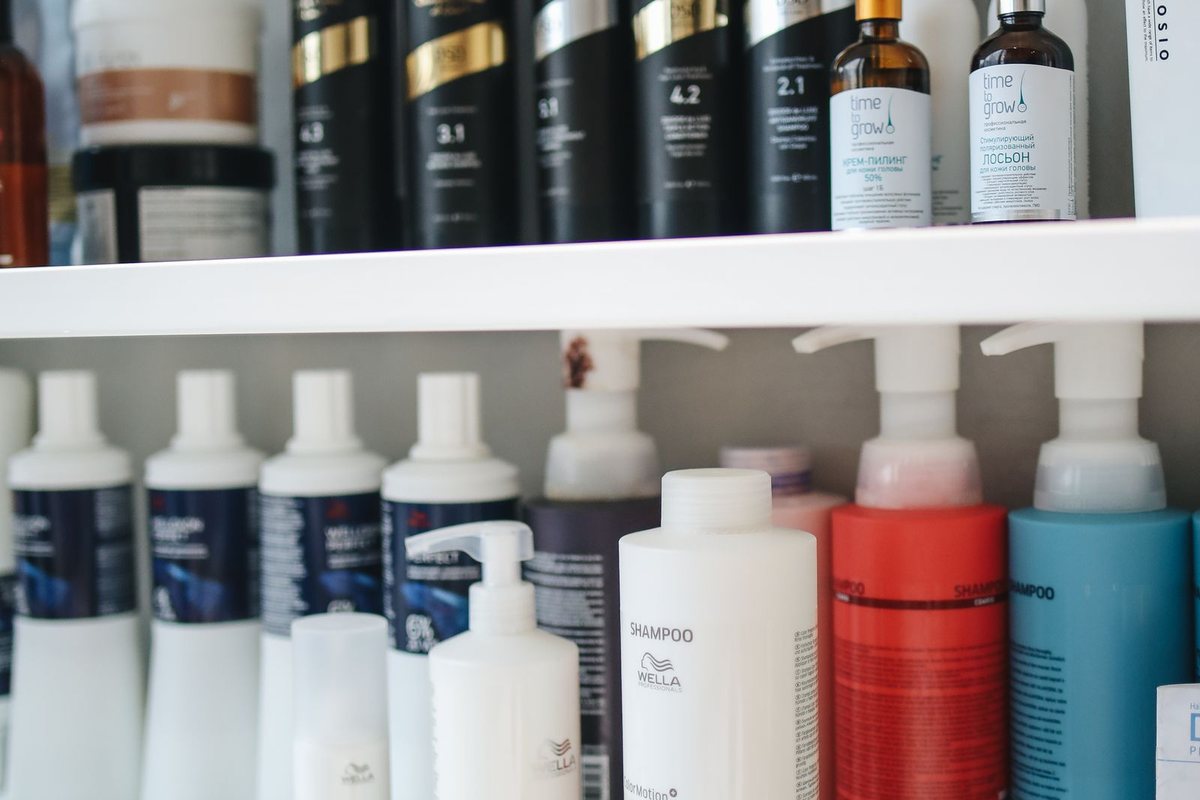 A variety of shampoo and conditioner bottles displayed neatly on a bathroom shelf.