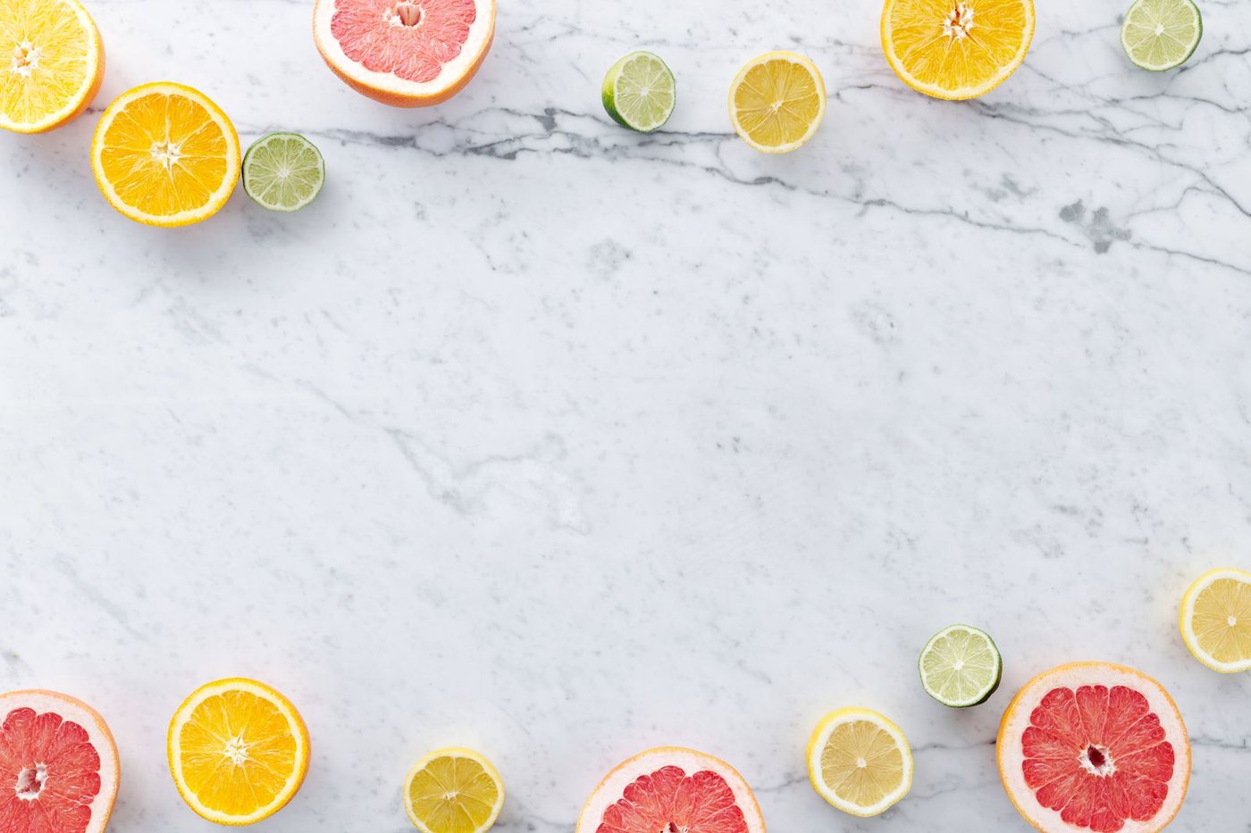 Flat lay of assorted citrus slices on a marble surface with ample copy space.